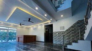 A spacious lobby with a marble floor, a reception desk, a staircase, and a high ceiling with recessed lighting. - Dreamland Resort (Kaladhungi)