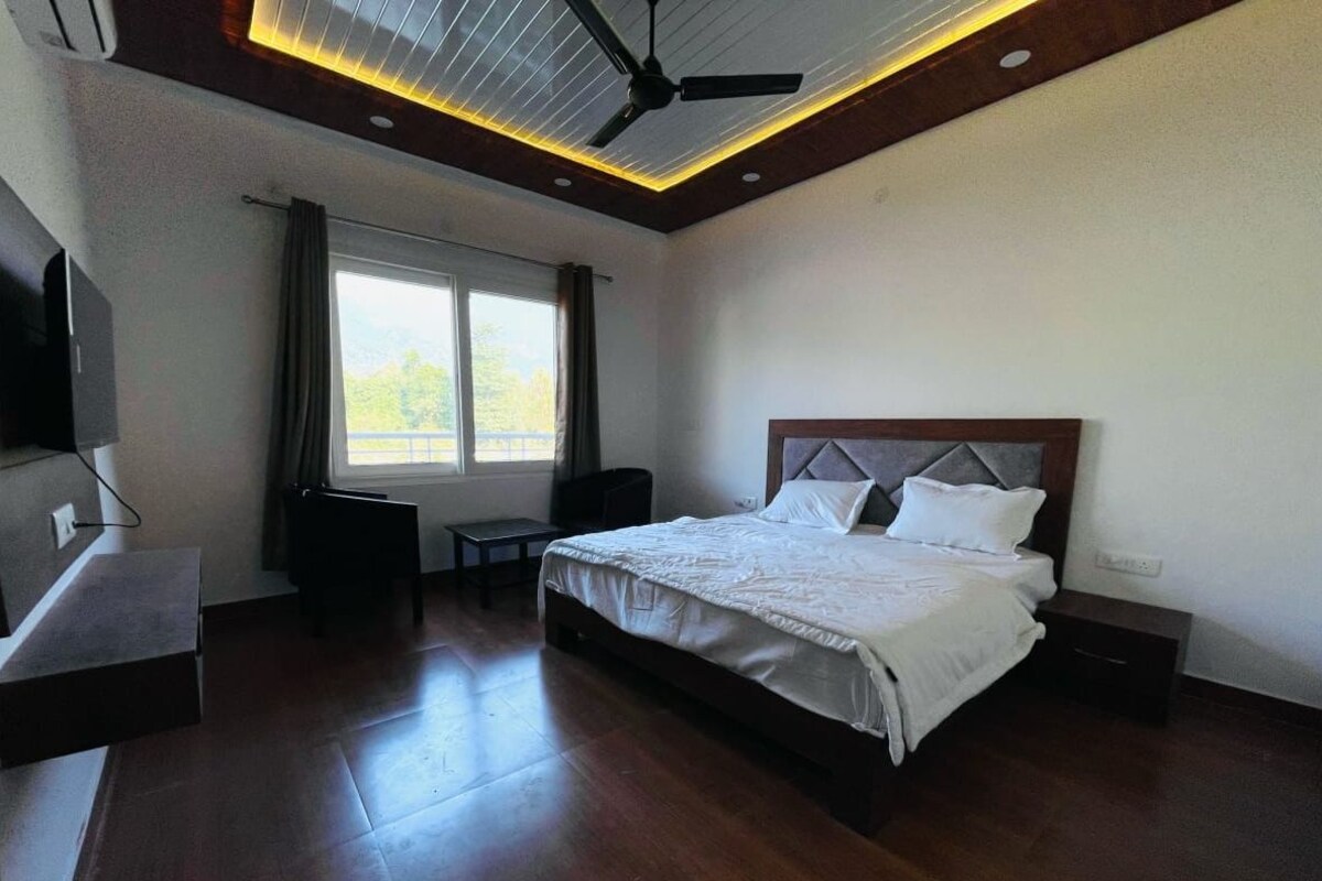 A modern hotel room with a large bed, a desk, and a ceiling fan.