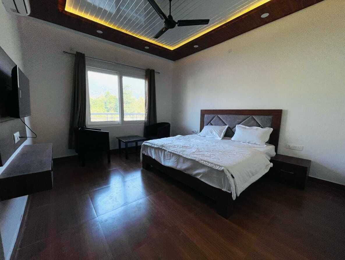 A modern hotel room with a large bed, a desk, and a ceiling fan.