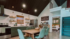 Une cuisine moderne avec un coin repas, comprenant une table et des chaises en bois, un coin café et un escalier menant à un niveau supérieur.