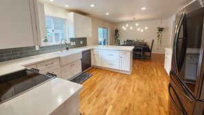 A modern kitchen with white cabinets, a stainless steel refrigerator, and a wooden floor. - Forest Retreat at Canyon Loop (Flagstaff)