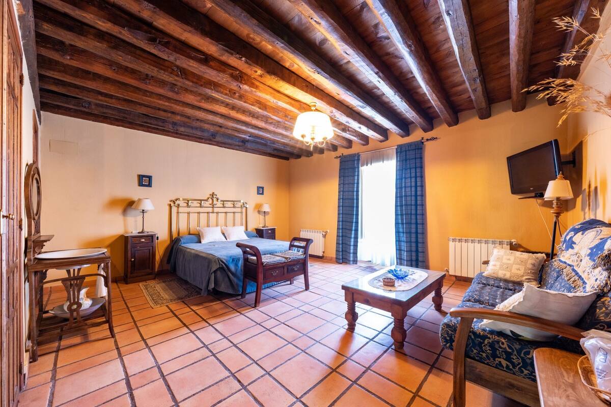 Une pièce avec un plafond en bois, un lit doté d’une tête de lit, un canapé, une table et un téléviseur.