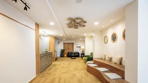Zona de recepción con mostrador de madera, área de espera con sillas, mostrador de recepción y pared con espejos circulares.