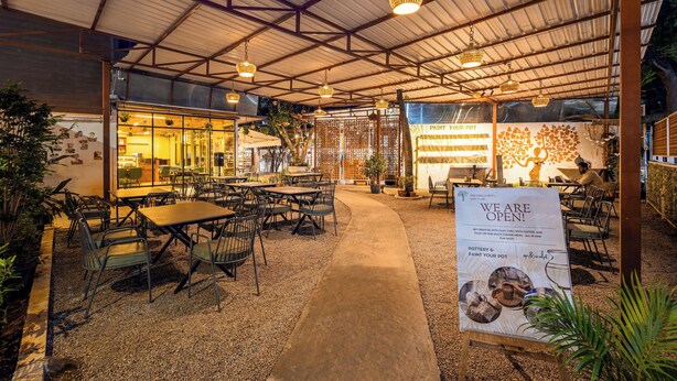Un café interior con mesas y sillas, un letrero y una pared decorativa.