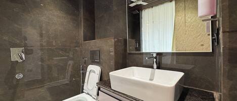 Un baño moderno con inodoro blanco, lavamanos y espejo.