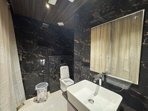 Un bagno moderno con una parete in marmo nero, un lavandino bianco e un water.