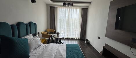 A hotel room with a bed, a desk, a chair, a television, and a ceiling fan.