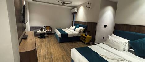 A modern hotel room with two beds, a desk, a chair, and a ceiling fan.