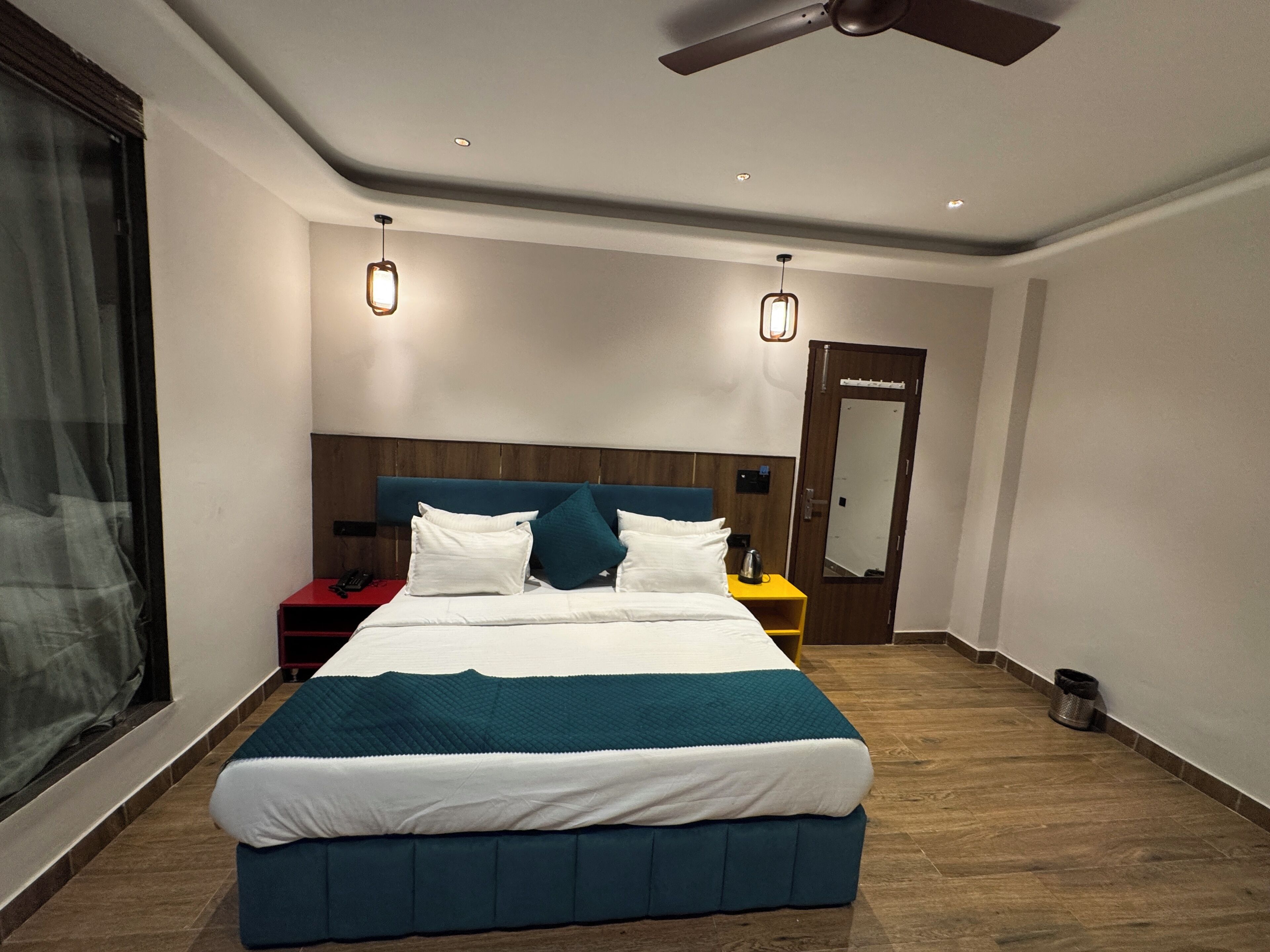 Moderni hotellihuone, jossa on suuri sänky, kattotuuletin ja yöpöytä, jossa on lamppu.