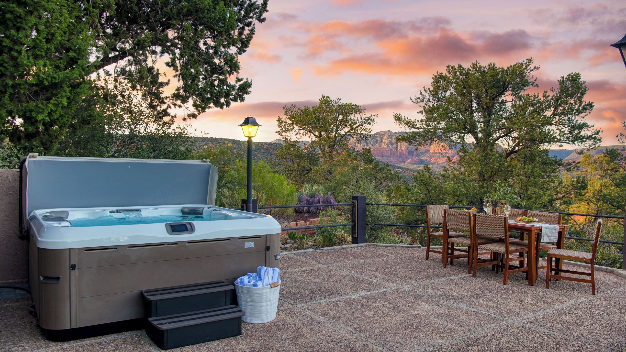A hot tub with steps, a table with chairs, and a scenic view of mountains.