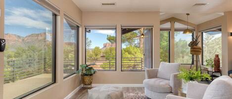 A sunlit room with large windows, a cozy seating area, and a view of the outdoors.