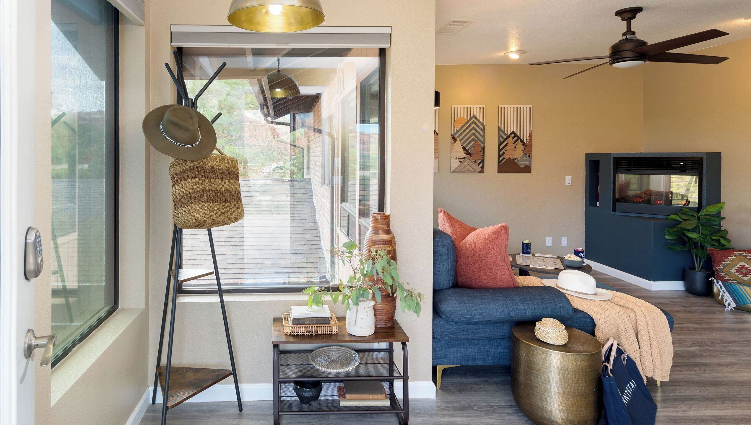 A living room with a sofa, a side table, a ceiling fan, and a window with blinds.