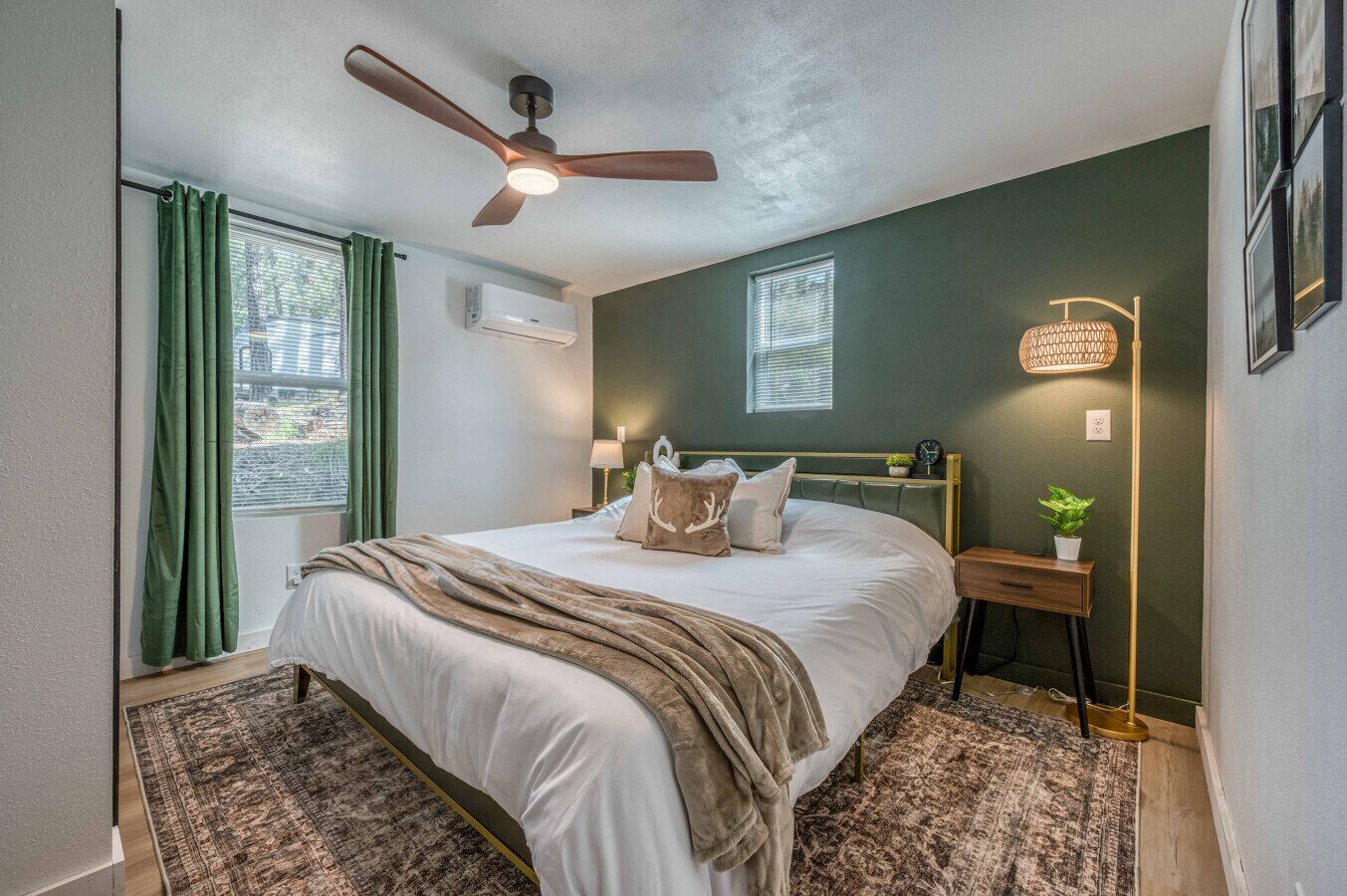 A bedroom with a bed, a ceiling fan, a bedside table with a lamp, and a window with curtains.