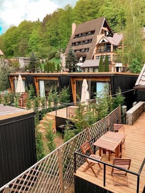 A modern building with a sloped roof, wooden deck, and outdoor seating area. - Moon Montana Busteni (Busteni)
