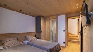 A bedroom with two beds, wooden ceiling, and a TV mounted on the wall. - Chalet at the foot of the slopes, private parking, free shuttle bus stop 50m away. (Les Deux Alpes)
