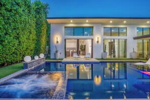 A modern house with a swimming pool, large windows, and outdoor seating.