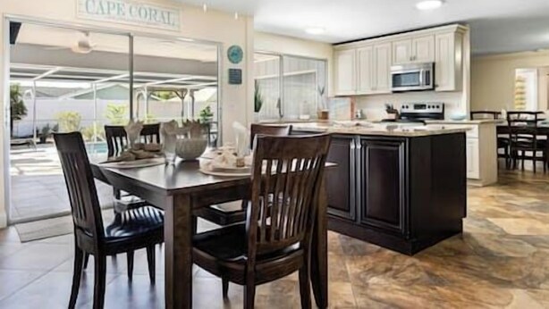 A modern kitchen with a central island, white cabinetry, and a ceiling fan. - Cape Coral Florida Getaway (Cape Coral)