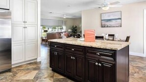 A spacious kitchen with dark wooden cabinets, a large island, and a stainless steel refrigerator. - Cape Coral Florida Getaway (Cape Coral)