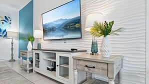 A modern living room with a large flat-screen TV mounted on a textured wall, a wooden console table with built-in shelves, and decorative vases. - LAKEVIEW from Your Private Pool! Relax & Create Memories! Resort Near Disney! (Kissimmee)
