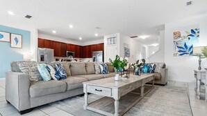 A modern living room with a grey sofa, a wooden coffee table, and a kitchen in the background. - LAKEVIEW from Your Private Pool! Relax & Create Memories! Resort Near Disney! (Kissimmee)