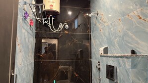 A modern bathroom with a marble wall, a shower area, and a hand dryer. - Kedar inn (Rishikesh)