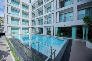 Un edificio moderno con piscina, varios balcones y ventanas amplias.