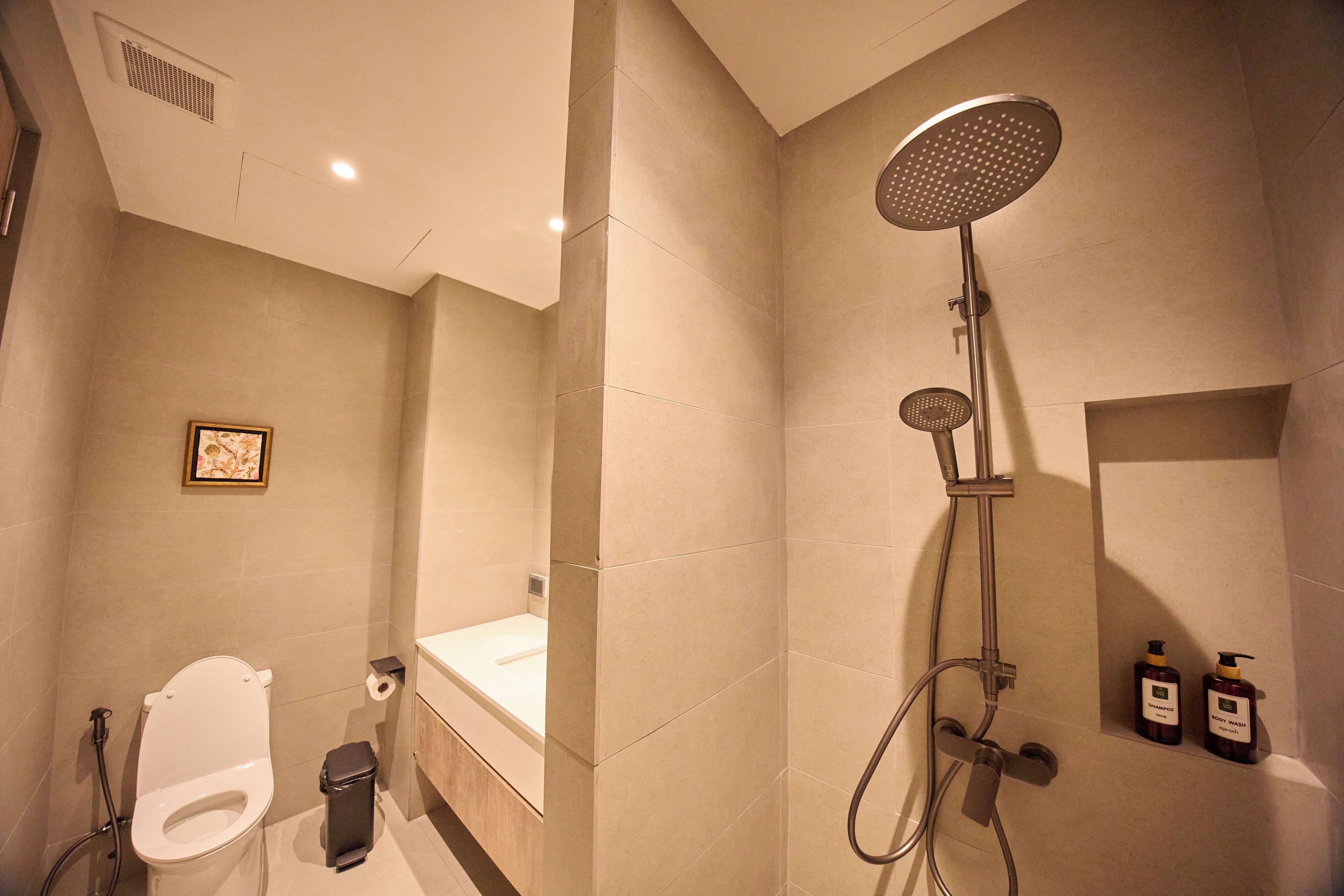 A bathroom with a toilet, sink, bathtub, shower, and two bottles of shampoo.
