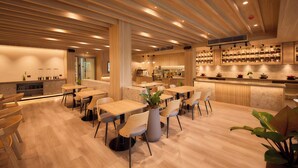 Un intérieur de restaurant moderne avec un plancher en bois, des tables, des chaises et un espace bar.