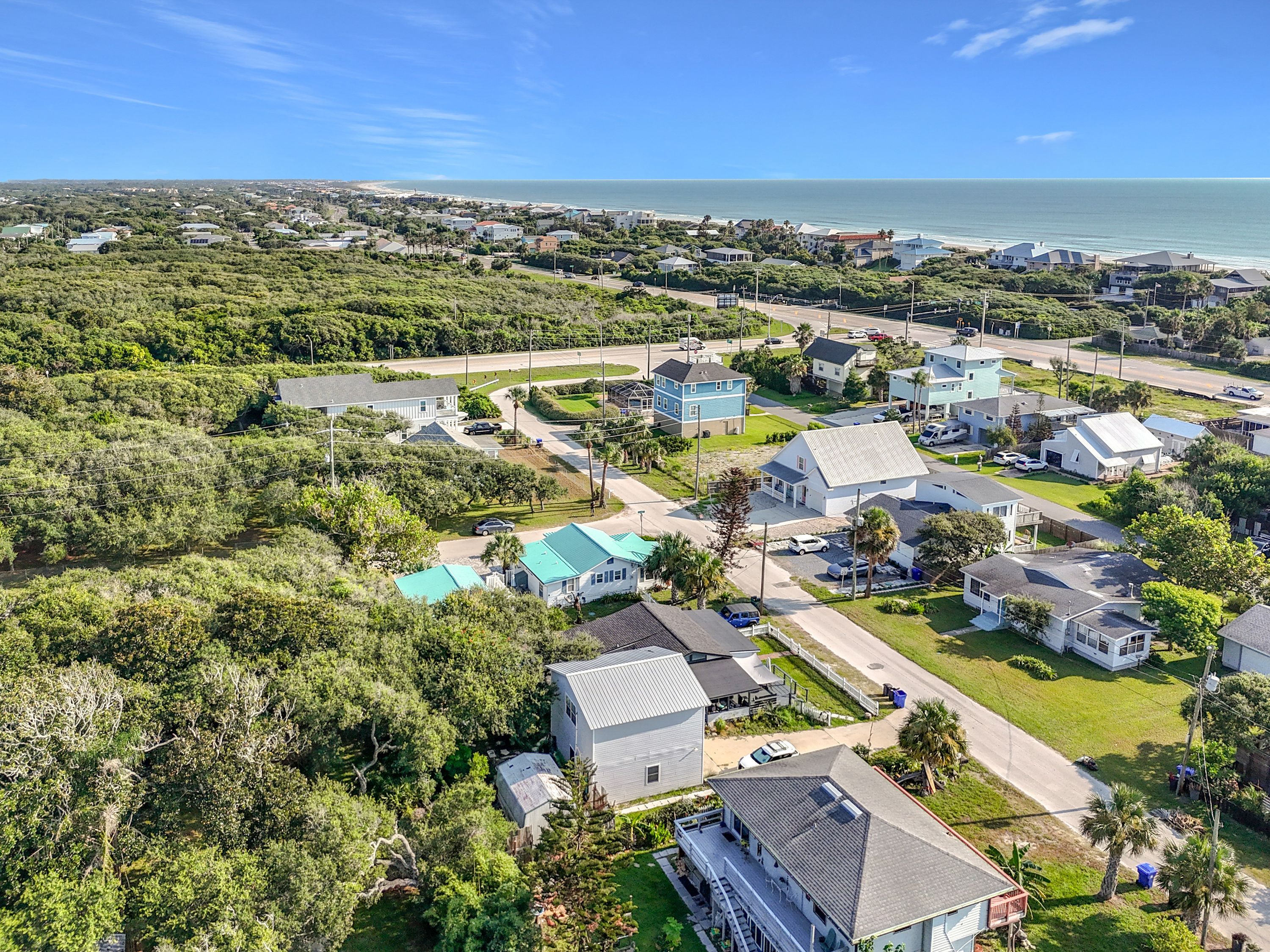 A residential area with houses, roads, and a beach in the background.