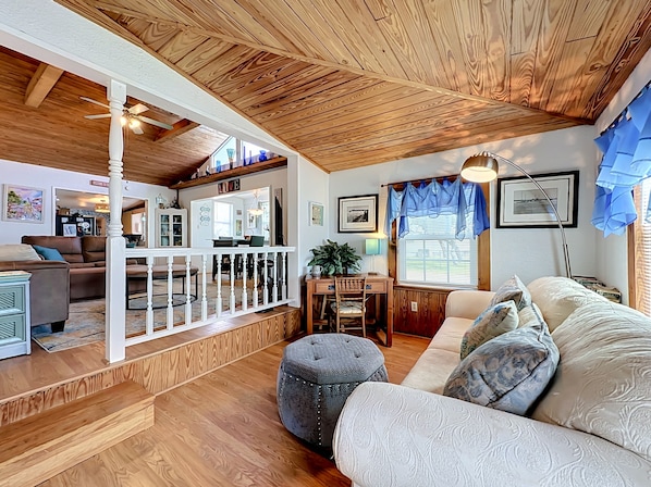A cozy living room with a wooden ceiling, a dining area, and a view of the kitchen. - Crescent Beach Cottage | Dog-Friendly (St. Augustine)
