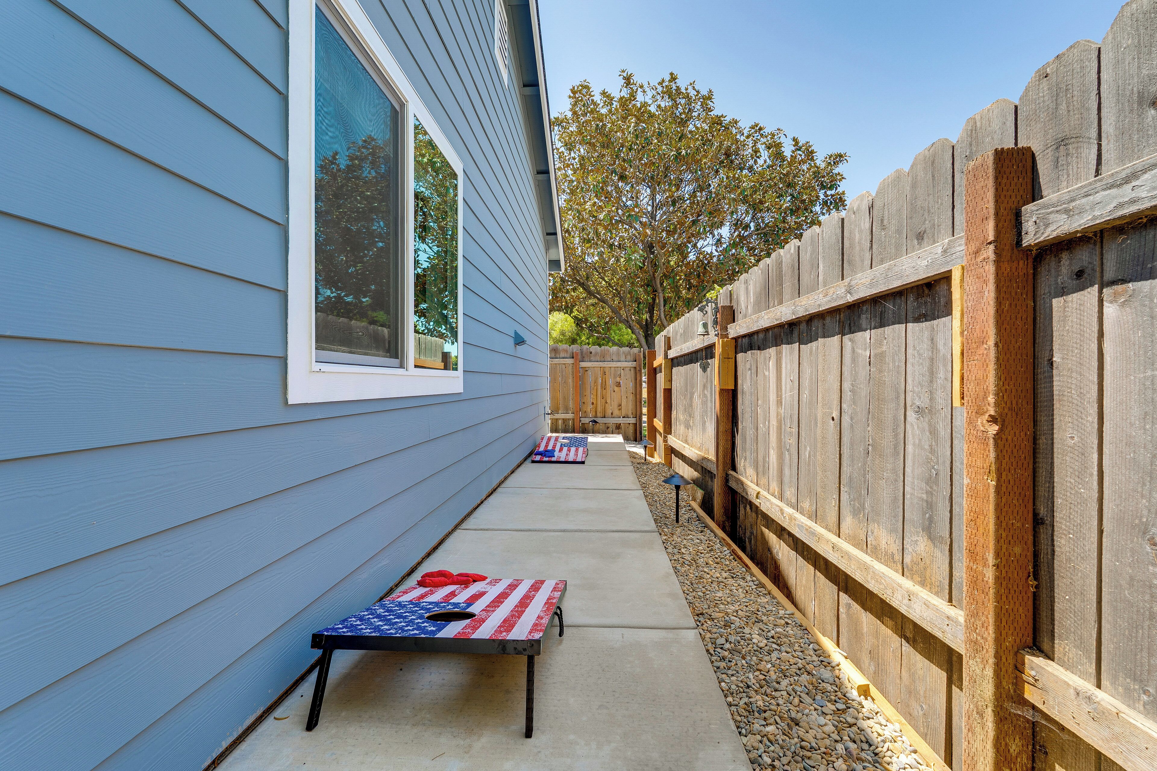 A patio with a wooden fence, a concrete pathway, and a small table with an American flag.