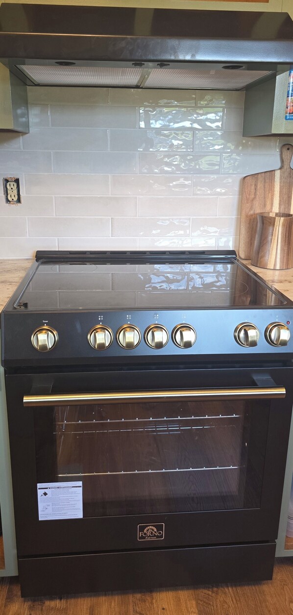 Un piano cottura nero con cinque fuochi e forno integrato.