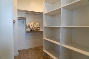 A walk-in closet with open shelving, a hanging rod, and a carpeted floor.
