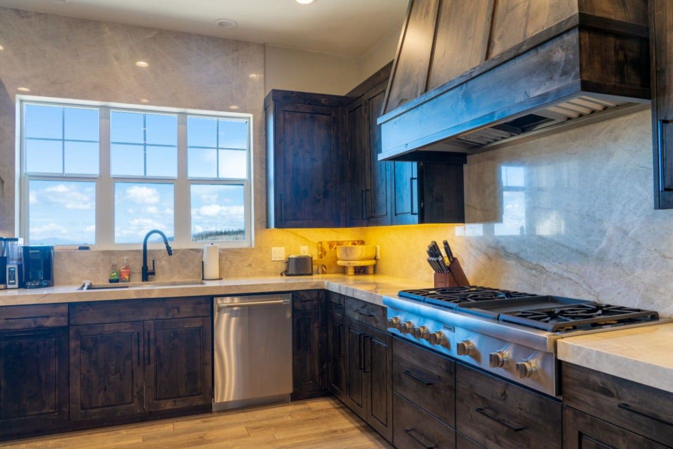 A modern kitchen with dark wood cabinets, a stainless steel dishwasher, and a gas stove.