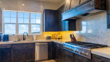 A modern kitchen with dark wood cabinets, a stainless steel dishwasher, and a gas stove.