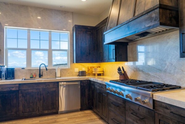 A modern kitchen with dark wood cabinets, a stainless steel dishwasher, and a gas stove.