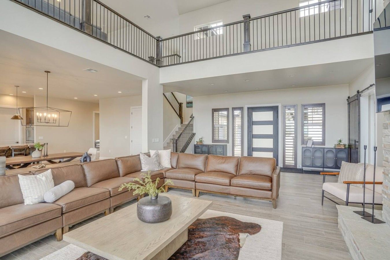 A spacious living room with a large L-shaped sectional sofa, a coffee table, and a staircase leading to an upper level.