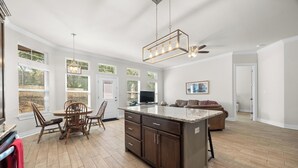 A spacious kitchen with a large island, wooden cabinets, and a dining area with chairs.