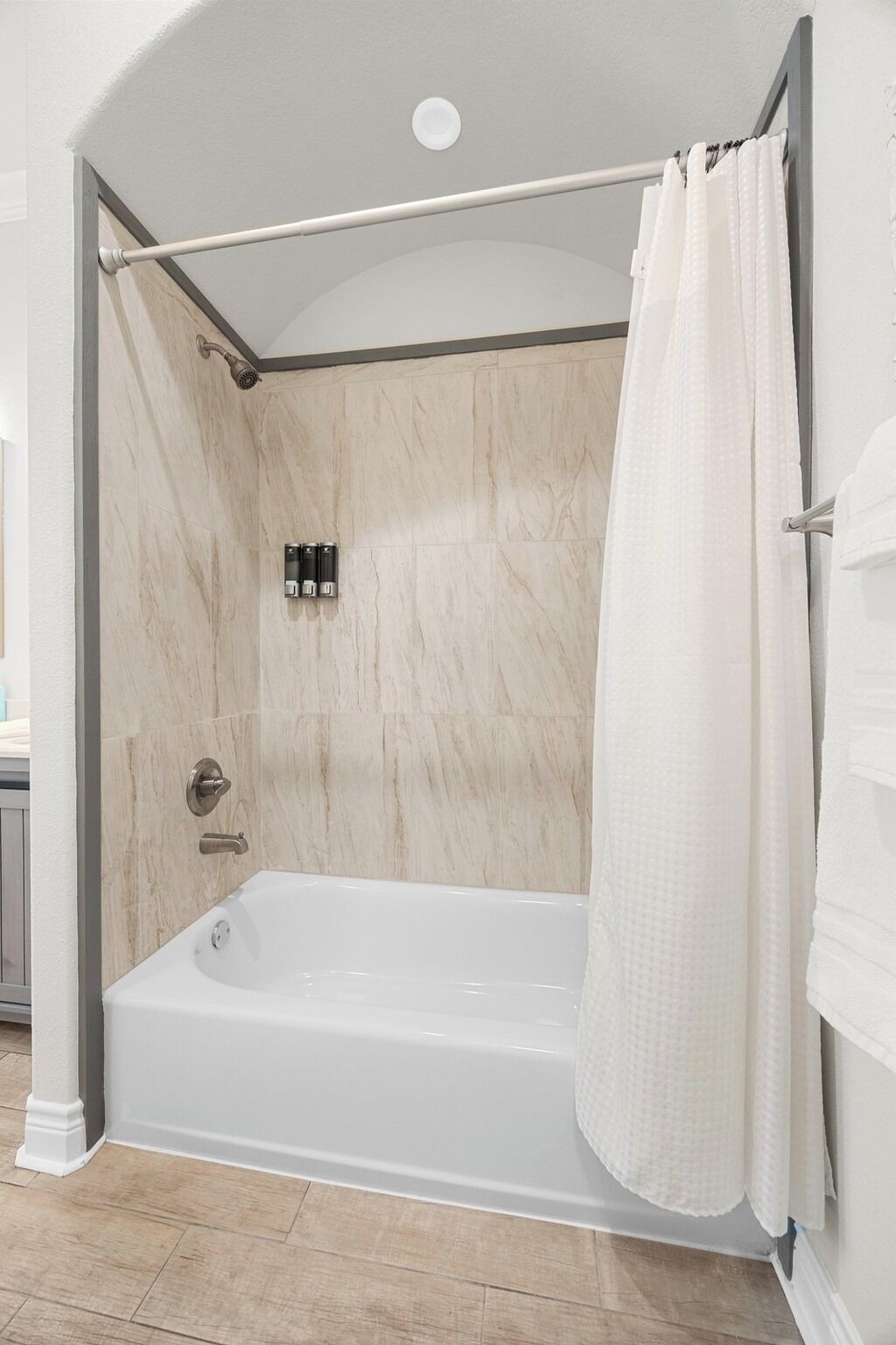 A walk-in shower with a glass door, a bathtub, and a towel rack.