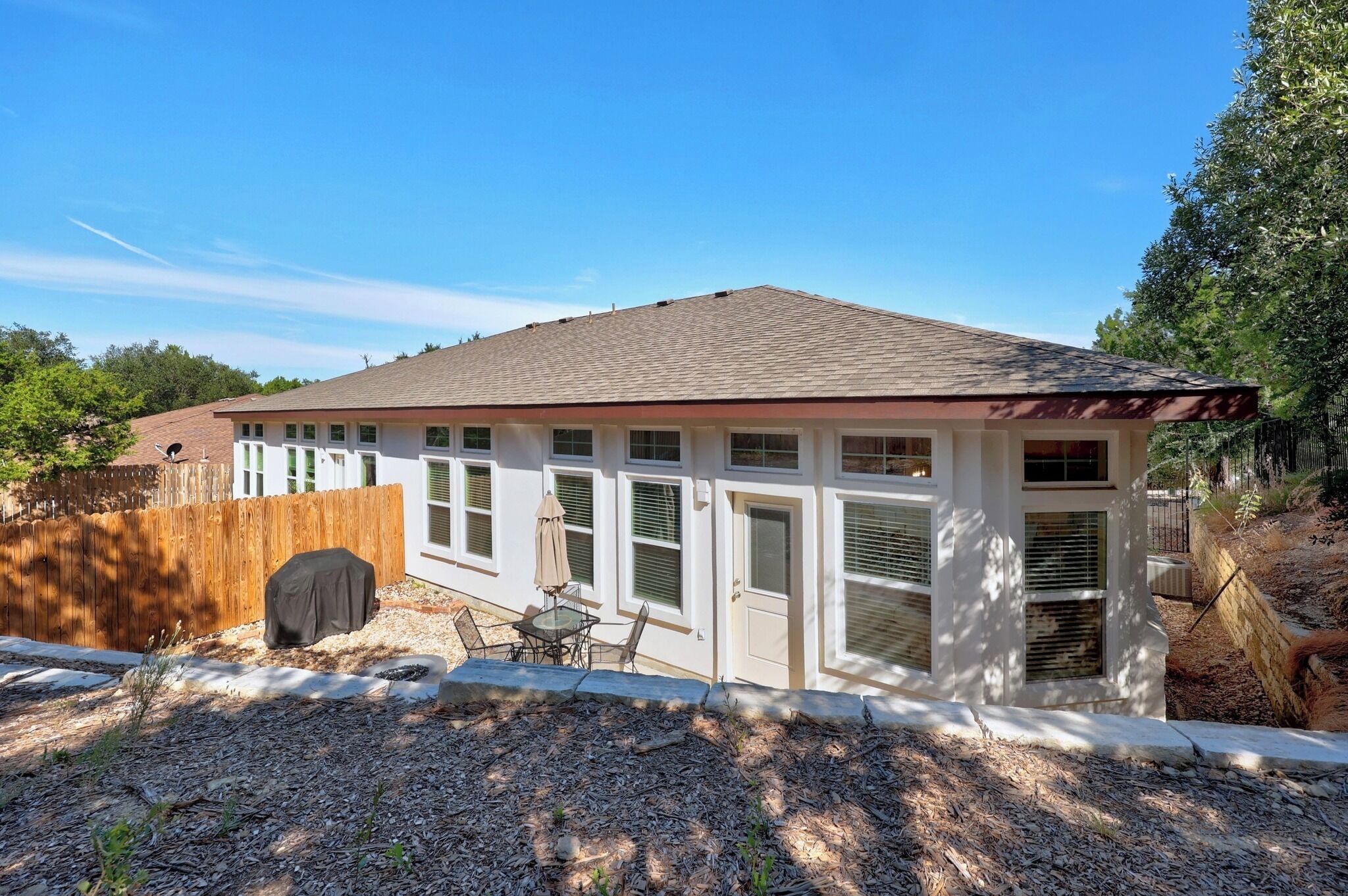Une maison de plain-pied dotée d’un patio couvert, d’une clôture en bois et d’une cour bien entretenue.