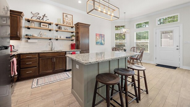 A modern kitchen with a central island, wooden cabinets, and a hanging light fixture.