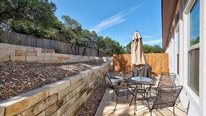 An outdoor patio with stone walls, a wooden fence, and a table with chairs.