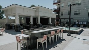 An outdoor bar area with a pool, seating, and a covered patio.