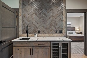 Een moderne badkamer met een backsplash van visgraat tegels, een marmeren aanrechtblad en houten kastjes.
