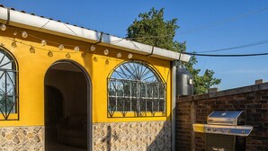 Un edificio giallo con facciata in pietra, un'ampia porta ad arco e un barbecue esterno.