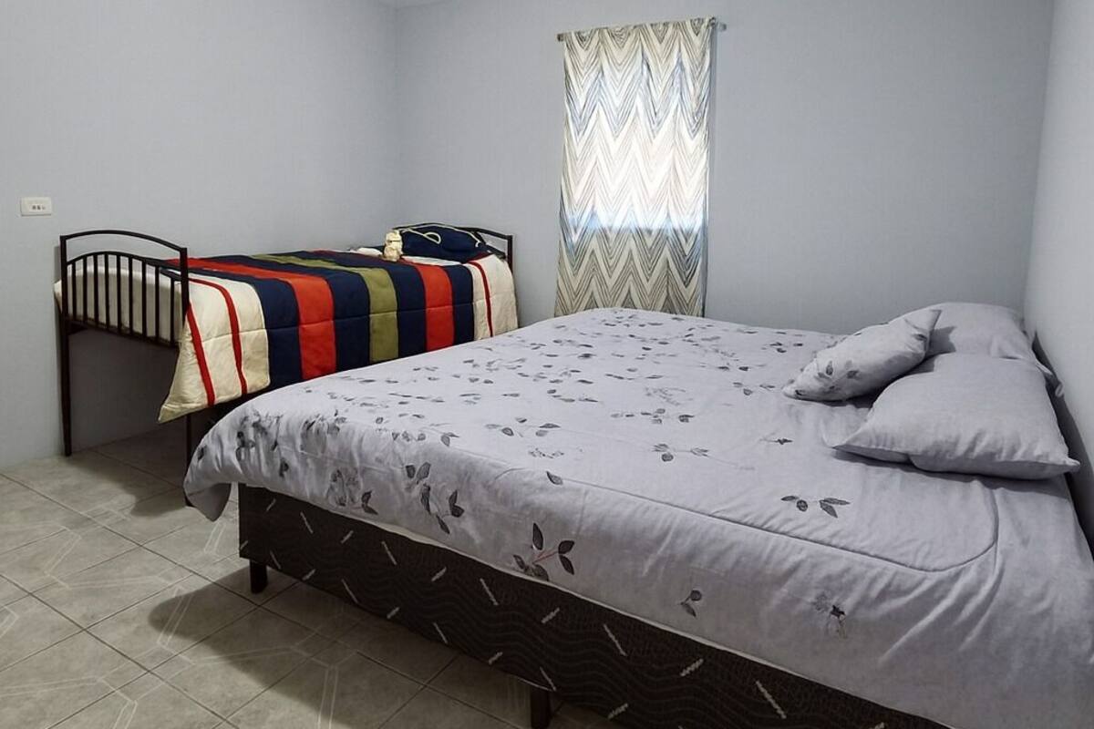 A bedroom with a single bed, a smaller bed, and a desk.