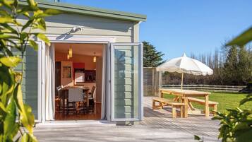 A modern house with a wooden deck, a dining area, and a large umbrella.