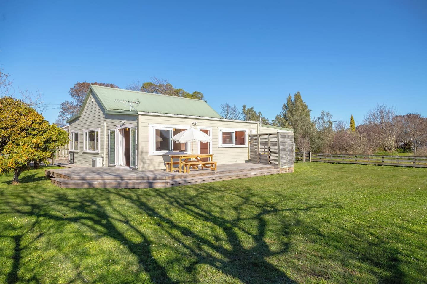 A single-story house with a covered patio, a wooden table and bench, and a small deck.