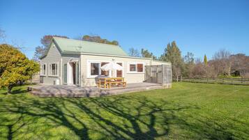 A single-story house with a covered patio, a wooden table and bench, and a small deck.