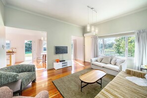 A spacious living room with a sofa, a coffee table, and a TV on a white stand.